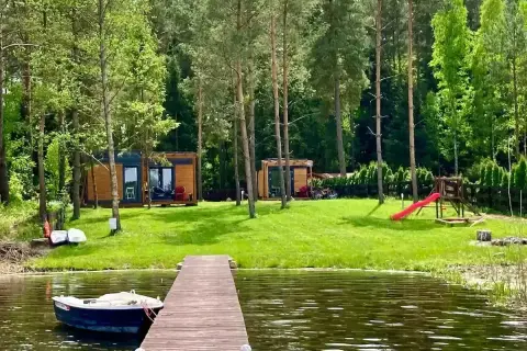 Domek nad jeziorem, łódka przy pomoście, plac zabaw i las – to piękne walory turystyczne Polski.