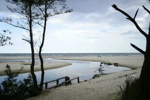 Plaża nad Jeziorem Żarnowieckim, z meandrującą rzeką wpadającą do morza. Idealne miejsce na relaks i podziwianie natury.