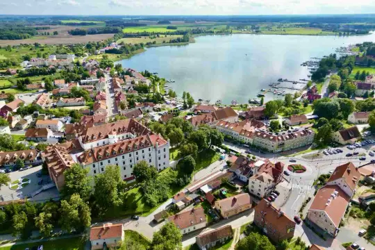 Widok z lotu ptaka na miasteczko nad jeziorem, z zamkiem i mariną. To jedno z najpiękniejszych miejsc na Mazurach, gdzie historia spotyka się z naturą.