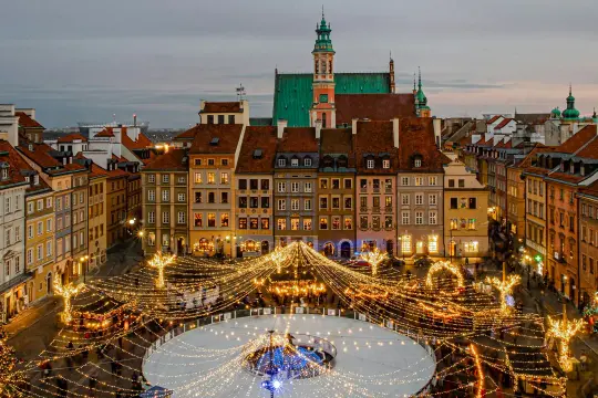 Magiczny zimowy wieczór w Warszawie. Rynek Starego Miasta rozświetlony tysiącami lampek, lodowisko i choinka tworzą idealną atmosferę na city break w Polsce.