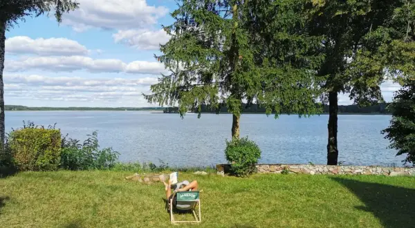 Osoba odpoczywa nad jeziorem, ciesząc się spokojem. To jedno z tych magicznych miejsc Kujawsko-Pomorskiego, gdzie czas płynie wolniej.