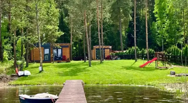 Domek nad jeziorem, łódka przy pomoście, plac zabaw i las – to piękne walory turystyczne Polski.