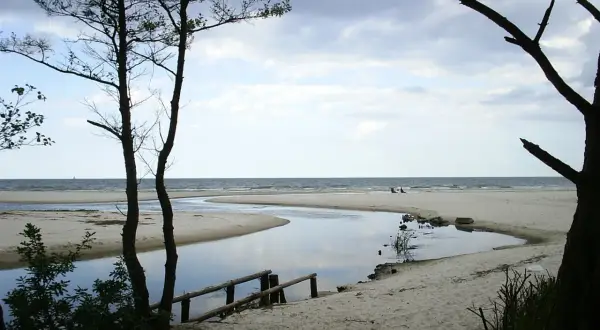 Plaża nad Jeziorem Żarnowieckim, z meandrującą rzeką wpadającą do morza. Idealne miejsce na relaks i podziwianie natury.